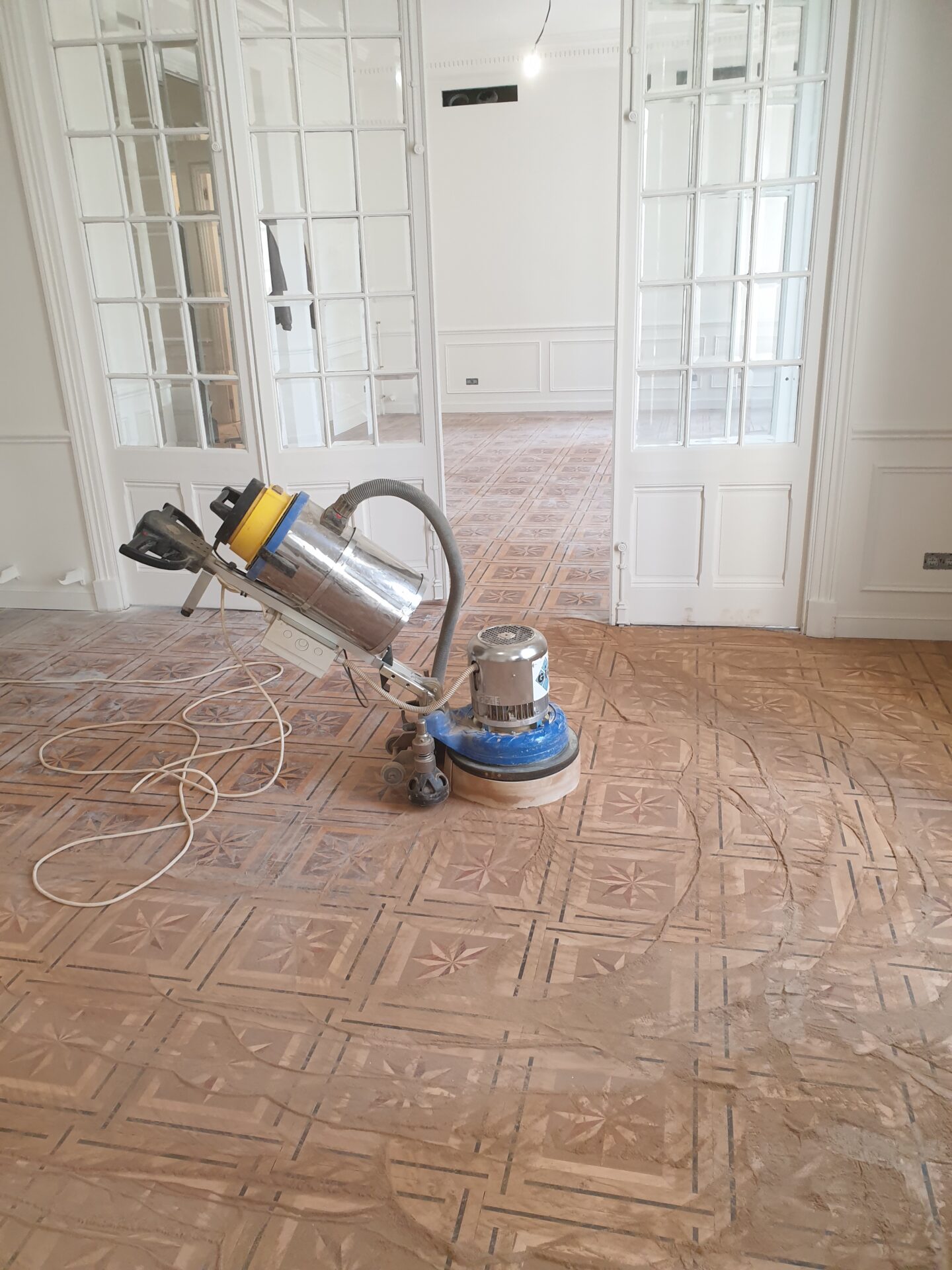 Une photo du ponçage d'un parquet avant vitrification