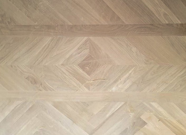 Le ponçage du tapis en parquet en bois